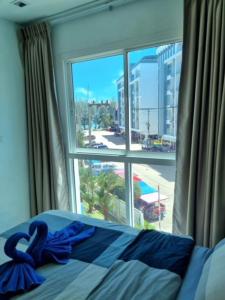 Schlafzimmer mit einem Fenster und einem Bett mit blauer Bettwäsche in der Unterkunft Grandblue 311 in Mae Pim