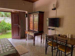 a bedroom with a table and a cabinet and a television at Agasthi Airport Close in Katunayaka