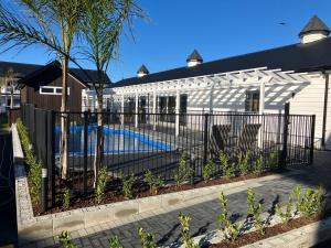 a fence with a swimming pool in front of a house at Newina Rotorua in Rotorua