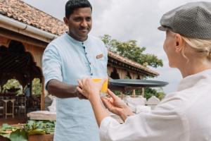 a woman is handing a man a plate at Malabar Hill in Weligama