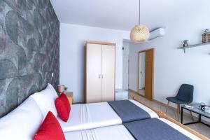 1 dormitorio con cama blanca y almohadas rojas en LUXURY ROOMS BURE en Murter
