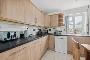 a kitchen with wooden cabinets and a black counter top at 3 Bed Semi sleeps 7 in Oxford in Oxford