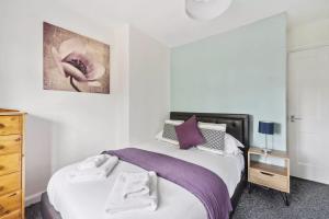 a bedroom with a bed with purple sheets and a dresser at 3 Bed Semi sleeps 7 in Oxford in Oxford