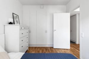 - une chambre avec des murs blancs, un lit et une commode dans l'établissement Brand new home in Barkabystaden, à Barkarby