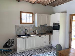 a kitchen with white cabinets and a table and chairs at Paardenhuisje in Sint-Lievens-Houtem