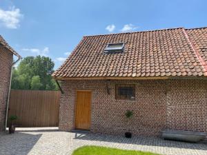 a brick house with a wooden door and a fence at Paardenhuisje in Sint-Lievens-Houtem