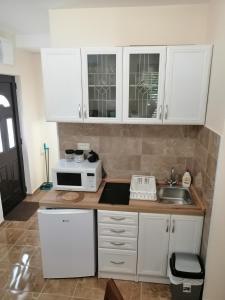 eine Küche mit weißen Schränken, einer Spüle und einer Mikrowelle in der Unterkunft Apartman Petovic in Kotor