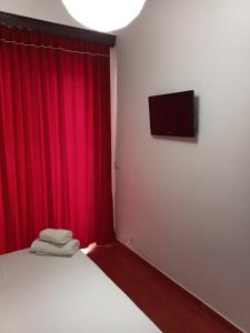 Hotel Villa Ruci في كساميل: غرفة نوم بسرير وستارة حمراء