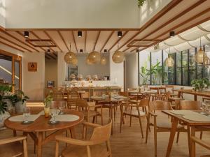 a restaurant with wooden tables and chairs and windows at The Motifs Eco Hotel - SHA Extra Plus in Chanthaburi