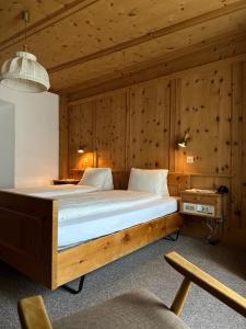 a large bed in a room with wooden walls at Hotel Acla Filli in Zernez