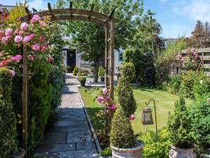 a garden with a wooden arch and flowers at The Moorings in Garlieston