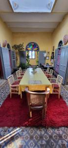 a dining room with a table and chairs on a red rug at La Maison Haute Larache Morocco in Larache