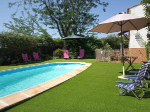 a swimming pool with lawn chairs and an umbrella at La Tierra Verde COTTAGE in Alcuéscar