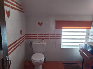 a bathroom with a toilet and a window with hearts on the wall at Appart privé 2 chambres en hyper centre in Le Tampon