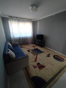 sala de estar con sofá azul y alfombra en 2-х комнатная квартира en Kyzylorda