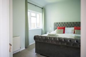 a bedroom with a large bed with red pillows at Birdsong & Pine: parking & garden in Worthing