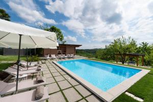 a swimming pool with chairs and an umbrella at Casa San Grato in Monteu Roero +29 photos