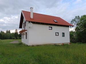 uma casa branca com um telhado vermelho num campo em Csencsó Vendégház em Ciumani