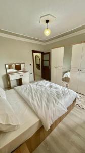 a bedroom with a large white bed and a desk at KUDÜS APART in Bostancı