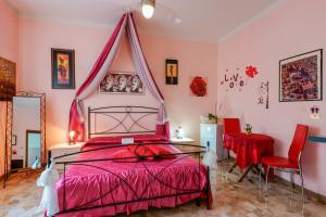 1 dormitorio con cama roja, mesa y sillas en Bed and Breakfast Dolce Vita Bologna, en Bolonia