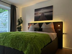 a bedroom with a large bed with a green blanket at EXCLUSIVES APARTMENT - Auszeit Mondsee in Mondsee