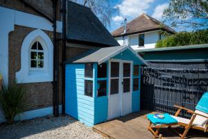 a blue shed on a deck next to a house at Birdsong & Pine: parking & garden in Worthing