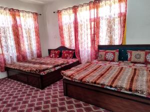 two beds in a room with curtains and windows at Hotel city way in Srinagar