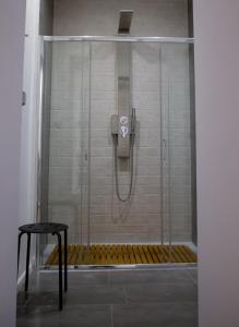 a shower with a glass door and a stool in a bathroom at La Piazzetta Suite in Potenza