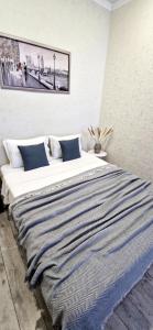 Una gran cama blanca con una manta a rayas. en INJU апартаменты, en Taldykolʼ