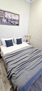 a large white bed with a striped blanket on it at INJU апартаменты in Taldykolʼ