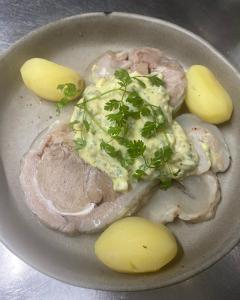 a plate of food with meat and potatoes on a table at Hotel le P'tit Beaumont in Beaumont-en-Auge