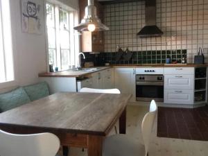 a kitchen with a wooden table and white chairs at CHARMING FARM HOUSE IN GUDHJEM in Gudhjem