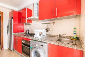 una cucina con armadi rossi e una lavatrice di Superbe appartement en résidence avec piscine a Skhirat