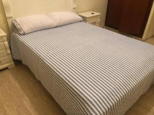 un letto con lenzuola a righe in una camera da letto di Superbe appartement en résidence avec piscine a Skhirat