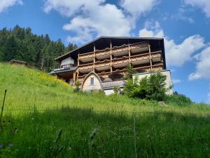 ein Gebäude auf einem Hügel mit einem Feld in der Unterkunft Das alpine Lifestyle Berghotel Madlener in Damüls