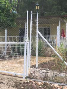 a chain link fence with a playground in front of a building at Village Garden Pansiyon in Cıralı