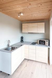 una cucina con armadi bianchi e soffitto in legno di Autant pour toi a Ciney