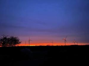 een groep windmolens in een veld bij zonsondergang bij Autant pour toi in Ciney