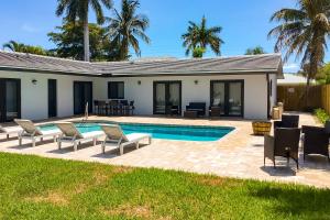 a swimming pool with chairs and a house at Deerfield Divine in Deerfield Beach