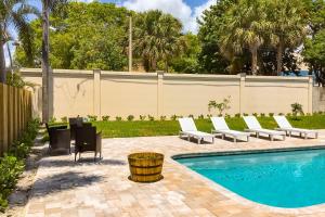a pool with lounge chairs next to a fence at Deerfield Divine in Deerfield Beach