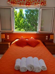 a bedroom with an orange bed with two towels on it at Potokia Rooms in Kakóvatos