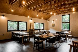 a dining room with tables and chairs and windows at Hotel Zátoka in Holčíkovce