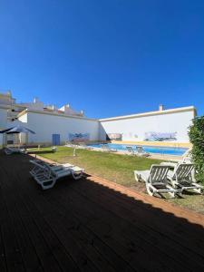 eine Gruppe von Liegestühlen auf einer Terrasse in der Nähe eines Pools in der Unterkunft Apartamento Falésia c/ Piscina in Albufeira