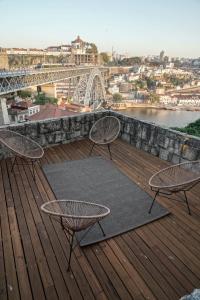 a deck with three chairs and a table and a bridge at Stay In Apartments - D. Hugo 23 in Porto