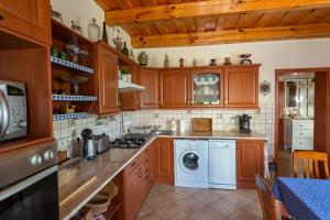 a kitchen with wooden cabinets and a washer and dryer at Völgykapu Vendégház in Monostorapáti