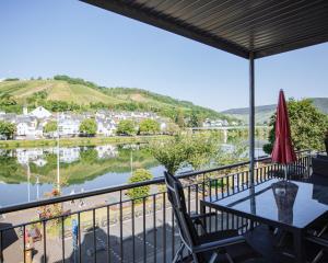 een balkon met een tafel en stoelen en uitzicht op een rivier bij Ferienhaus Moselpromenade in Zell an der Mosel