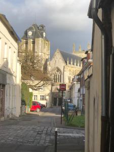 a city street with a church and a red car at LE GITE DE LA GIRAFE CENTRE VILLE LOUVIERS in Louviers