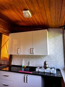 a kitchen with white cabinets and a black counter top at Maneviga Cafe & Apart in Uzungol