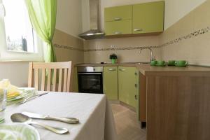Apartments Miljanic في كافتات: مطبخ مع دواليب خضراء وطاولة مع قطعة قماش بيضاء
