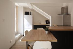 a kitchen with a wooden table and white chairs at Taote - Studio avec terrasse au Coeur de ville in Brignoles +12 photos